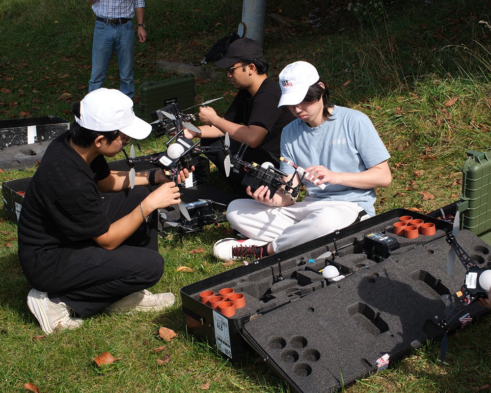 Three students install batteries in drones