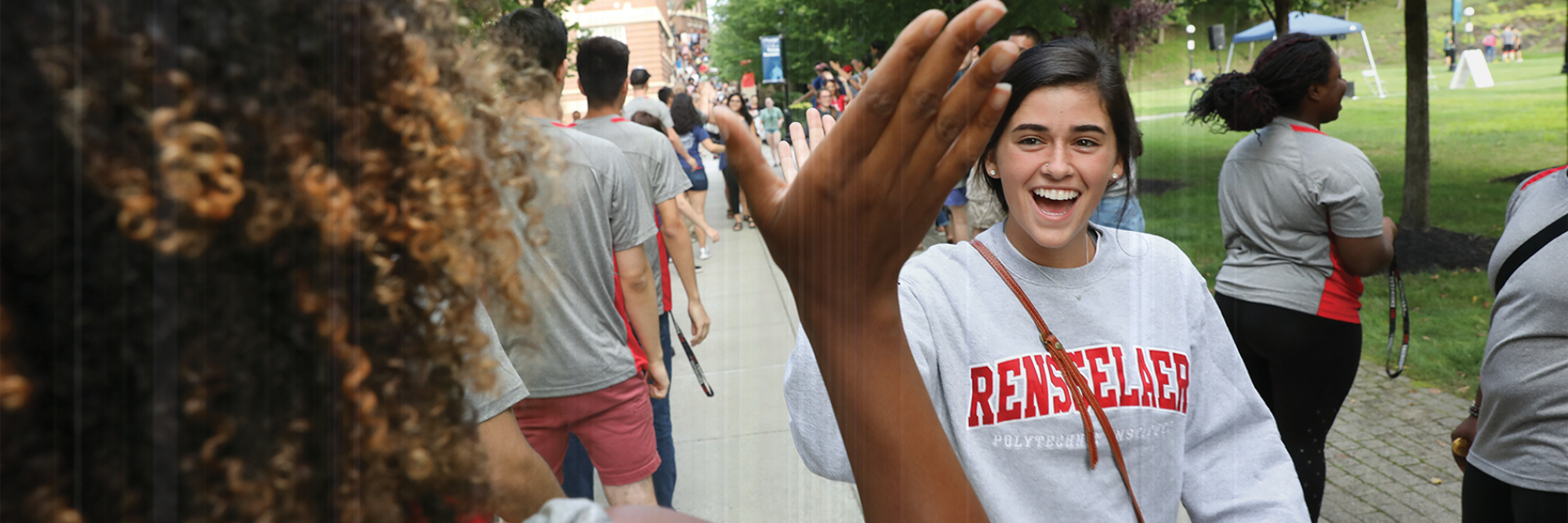 Student in Rensselaer sweatshirt gets high-fived by a friend